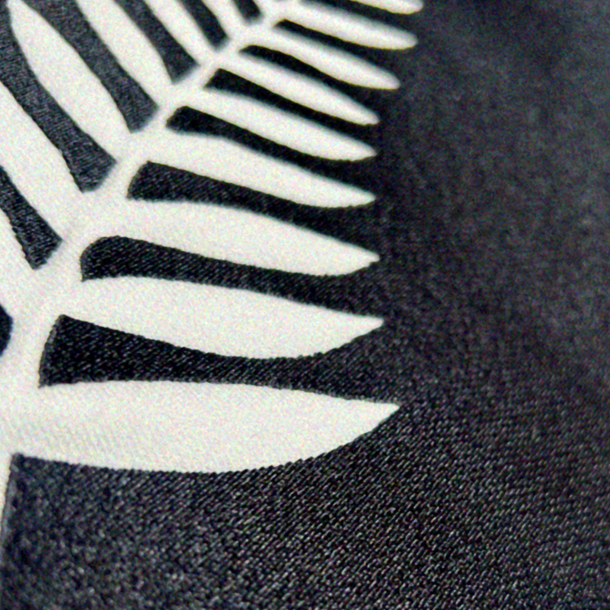 Close up image of the embroidery of on on the hoodie. Image shows white Fern leaf on black background, which is the symbol for New Zealand